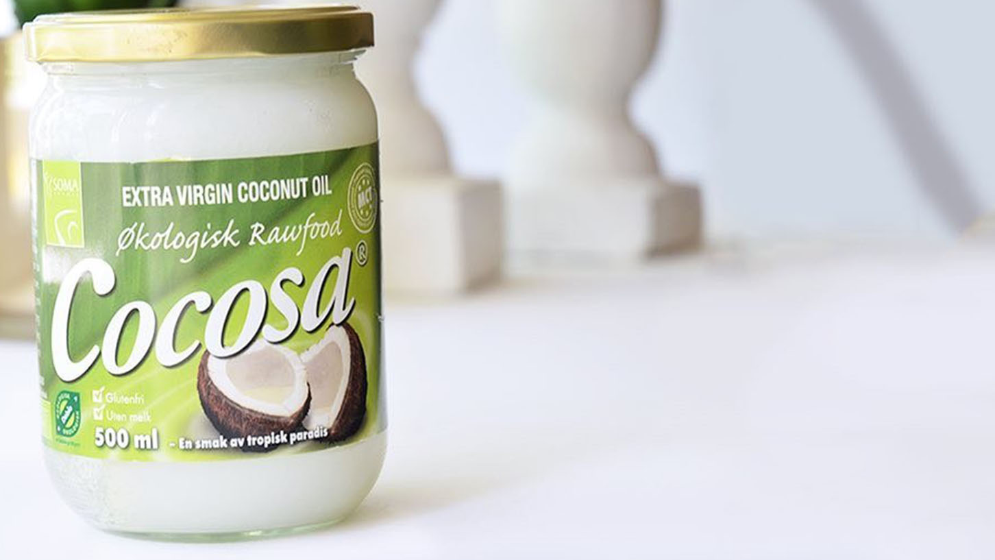 En uåpnet kruppe med Cocosa extra virgin coconut oil på et hvitt bord