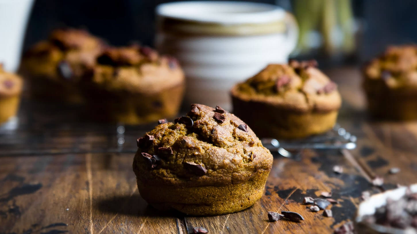 Flere deilige, veganske og glutenfrie sjokolade muffins baket med johannesbrodkjernemel, på et bord av mørkt tre.