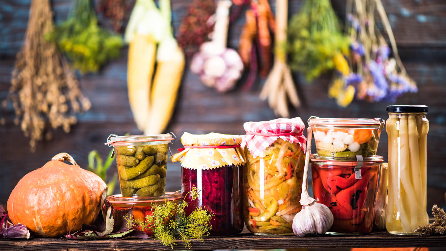 Diverse glass med fermenterte og syltede grønnsaker står på en kjøkkenbenk