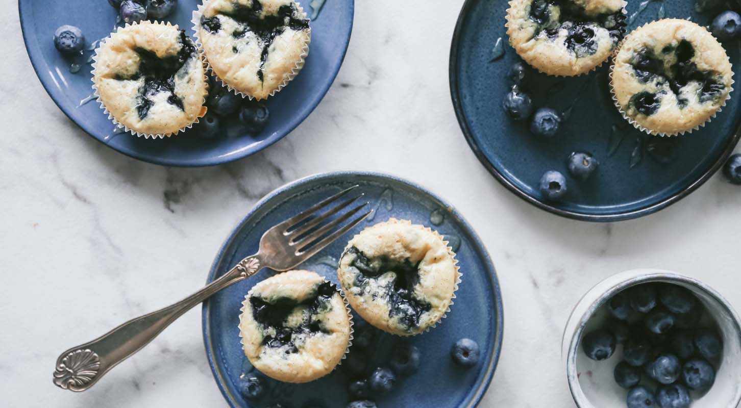 Pannekakemuffins på blå tallerkener dandert med blåbær.